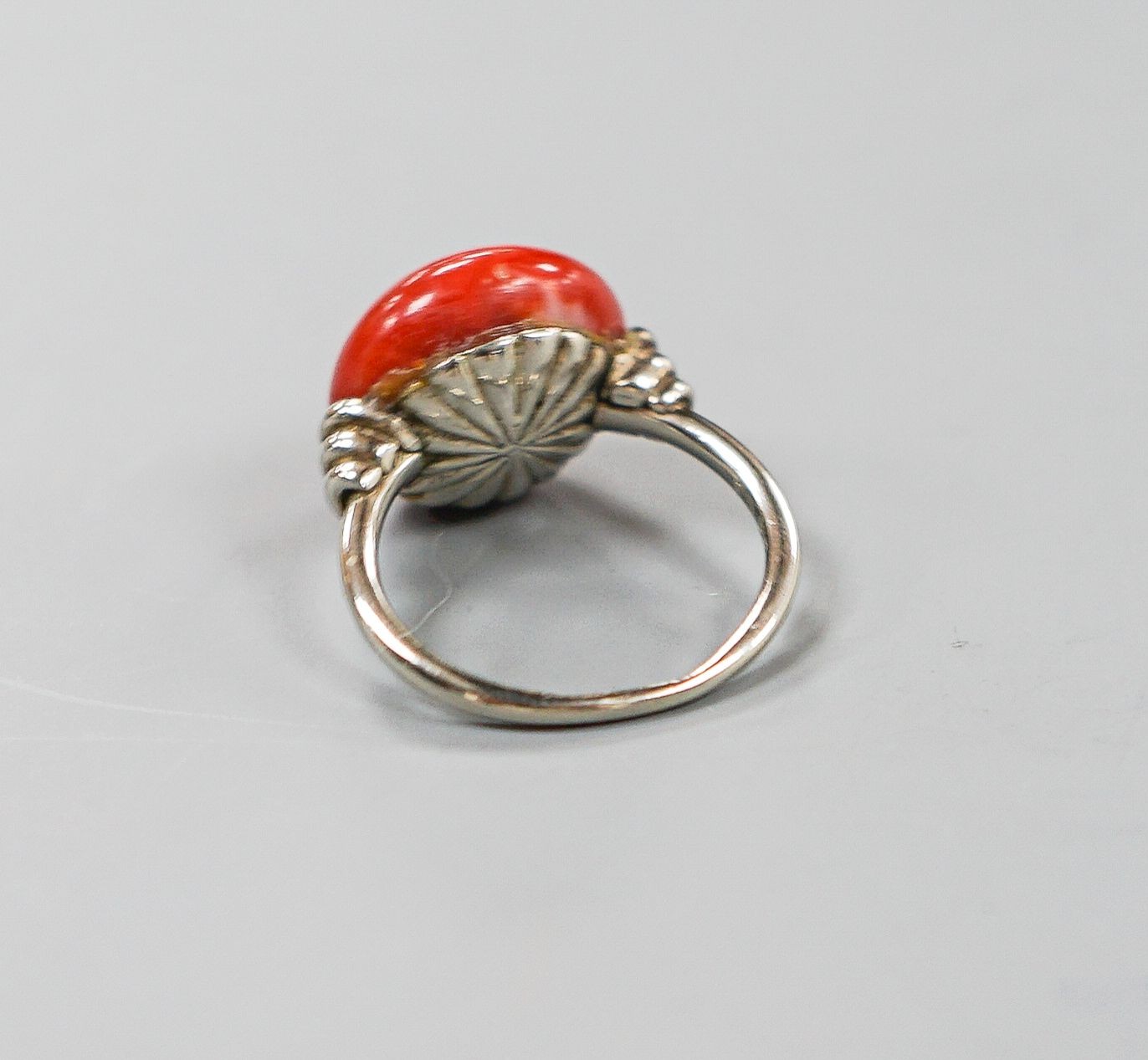 A 585 white metal and stained? cabochon coral set dress ring, size I, gross weight 5.5 grams.